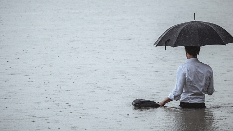 Mann mit Regenschirm im See